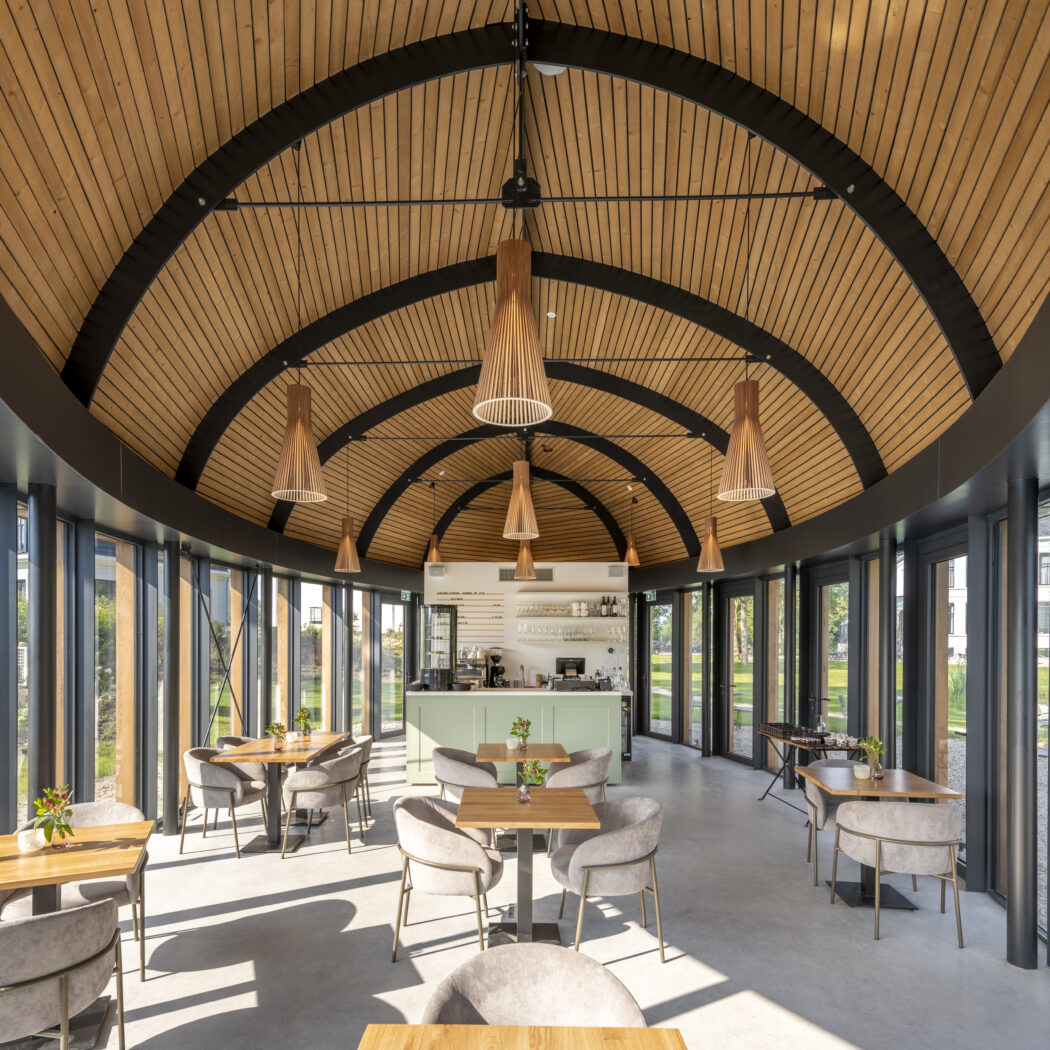 Modern café interieur met gewelfd houten plafond, glazen wanden en mintgroene bar met zitplaatsen.