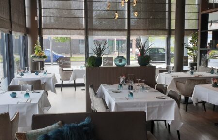 Interieur van Restaurant Silver met gedekte tafels, moderne inrichting en uitzicht op de straat door grote ramen.