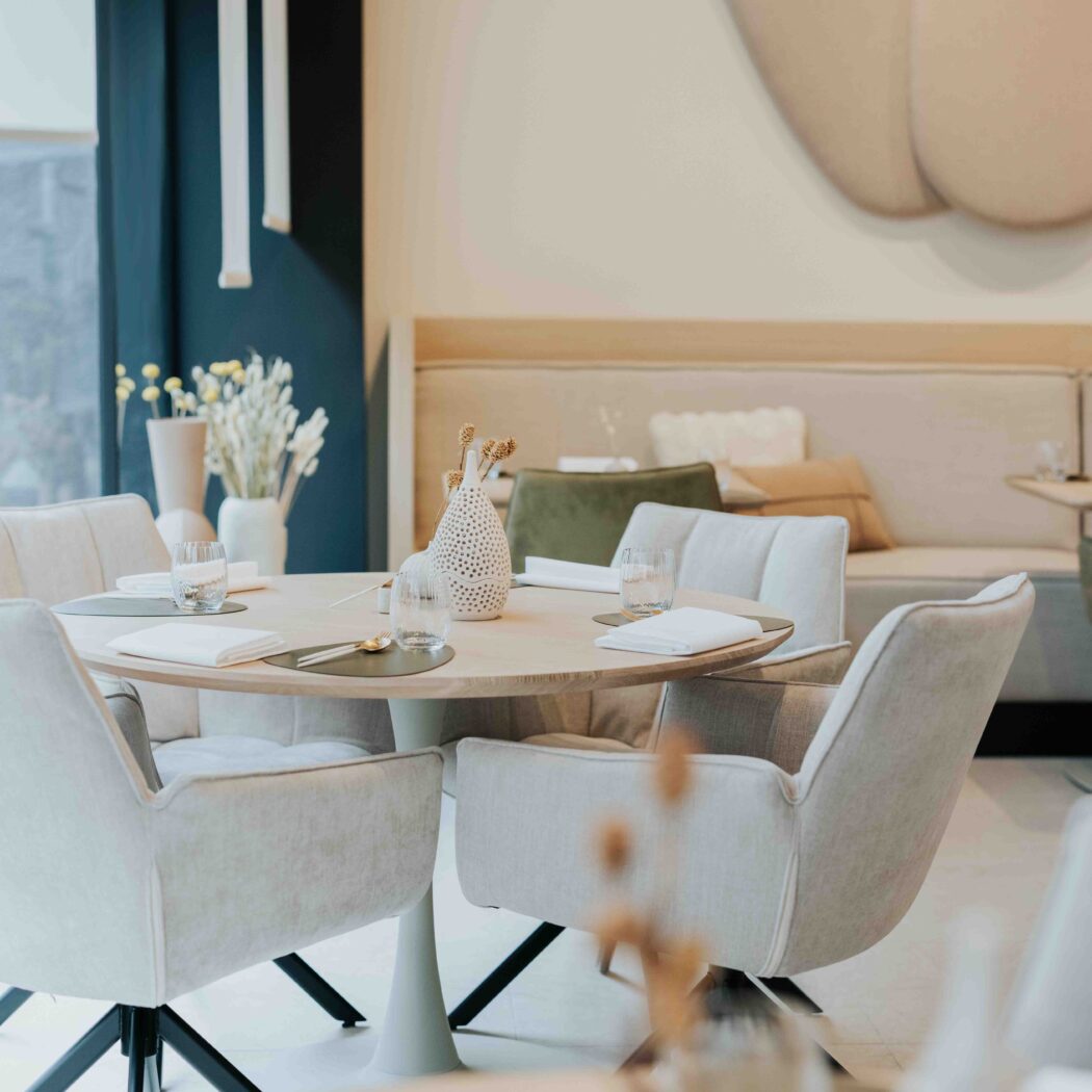 Stijlvolle, gedekte ronde eettafel met beige stoelen in een modern restaurant.