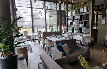 Modern restaurantinterieur met gedekte tafels, zitmogelijkheden en Restaurant Silver bordjes bij grote ramen.