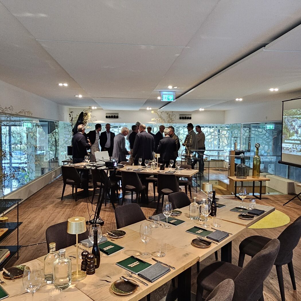 Zakelijke bijeenkomst in een modern ingerichte ruimte met gedekte tafels en projectiescherm.