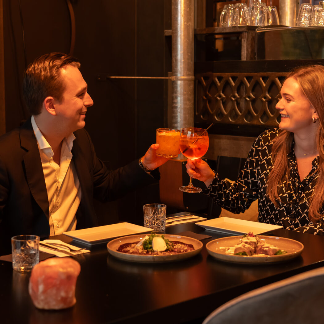 Lachend stel proost met kleurrijke cocktails bij een diner in een restaurant.
