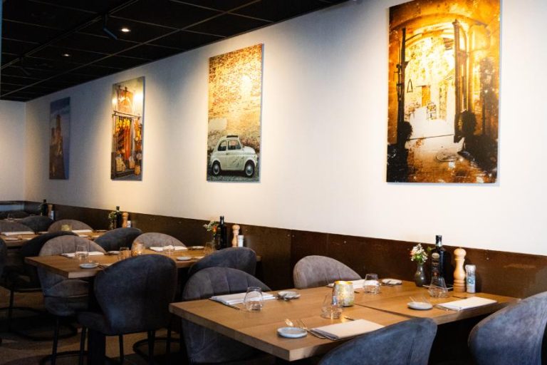 Gezellig restaurant interieur met gedekte houten tafels en sfeervolle Italiaanse wanddecoratie.