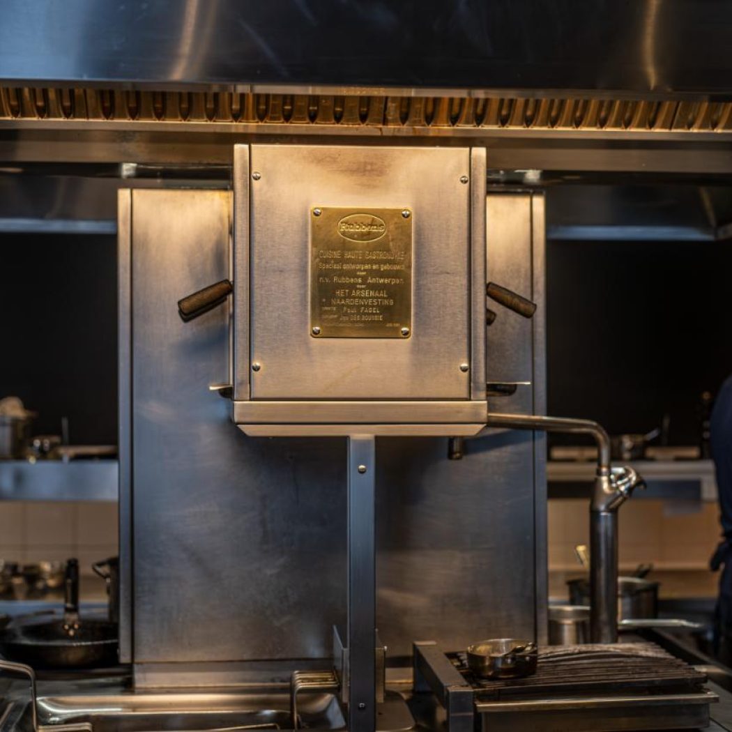 RVS professionele keuken met centrale Rubbens kookunit, bronzen Cuisine Haute Gastronomie plaat en chef.