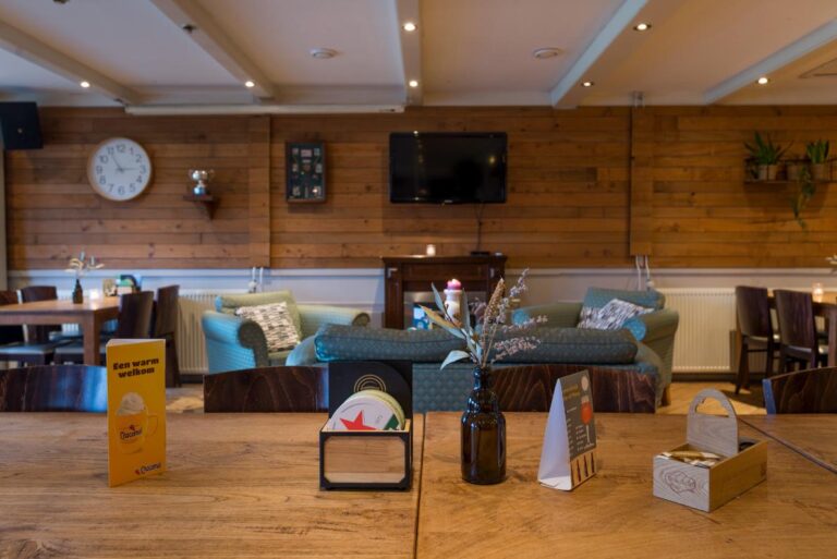 Houten tafel met een Een warm welkom kaartje en bieronderzetters in een gezellig café- of restaurantinterieur.