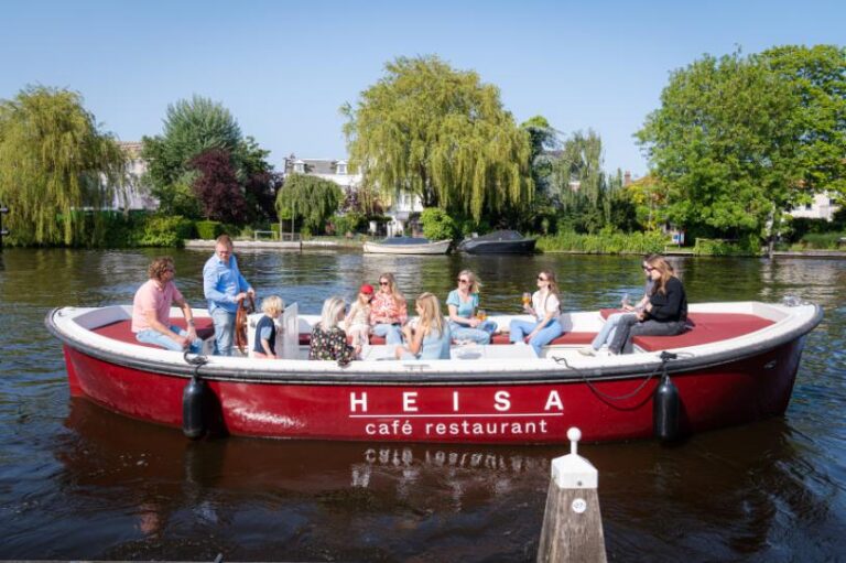 Mensen varen ontspannen in een rode HEISA café restaurant sloep op zonnig water.