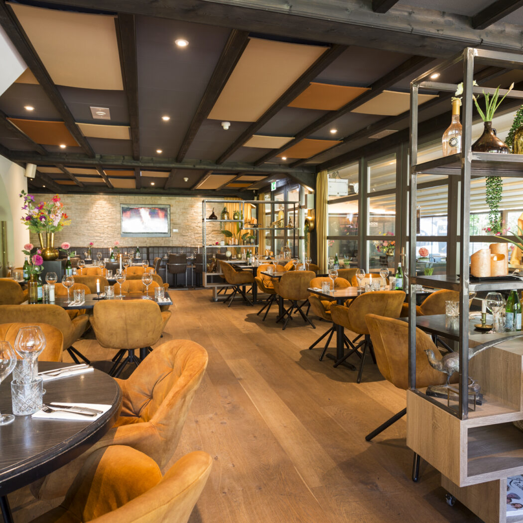 Elegant restaurantinterieur met houten vloer, vele oranje stoelen, ingerichte tafels en een decoratieve rek.