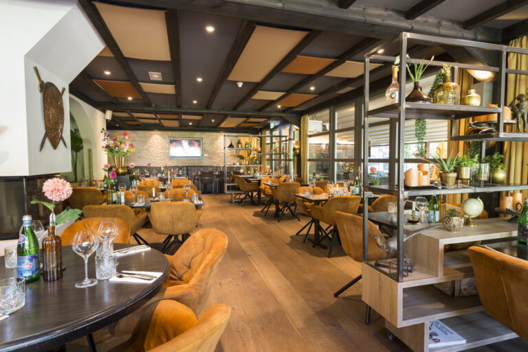 Elegant restaurantinterieur met houten vloer, vele oranje stoelen, ingerichte tafels en een decoratieve rek.