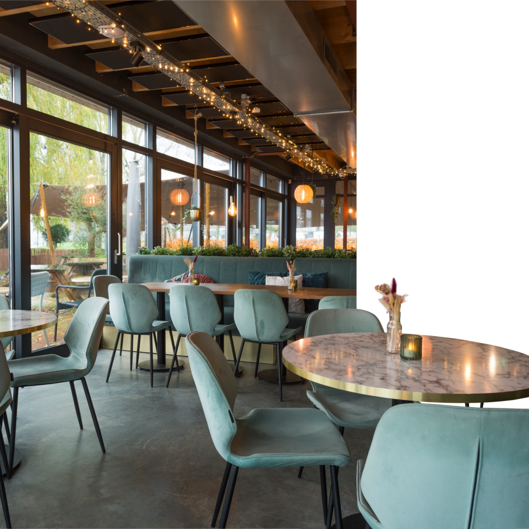 Restaurant interieur met mintgroene velours stoelen, marmeren tafels en grote ramen naar terras.