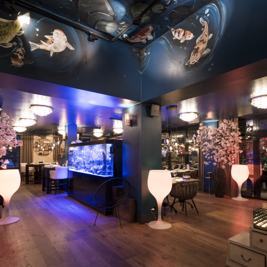 Sfeervol restaurantinterieur met koi-plafondschilderingen, een groot aquarium en roze bloesemdecoratie.