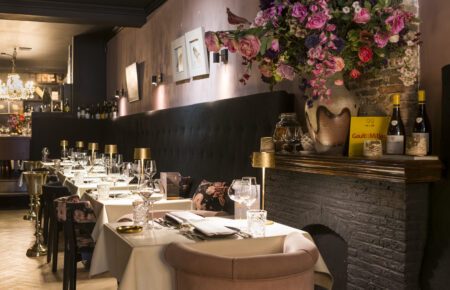 Restaurant interieur: gedekte tafels, bloemenarrangement, schouw.