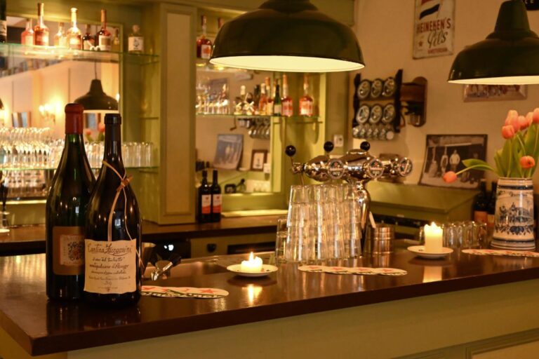 Warme barinterieur met Cantina Zaccagnini wijnflessen, brandende kaarsen, biertaps en Heineken details op de houten toonbank.