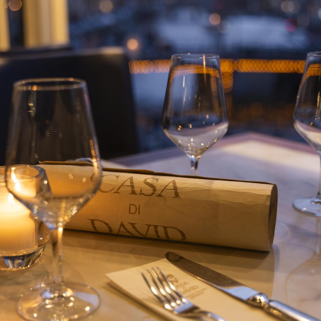 Elegant gedekte dinertafel met wijnglazen, kaarslicht en opgerold menu CASA Di DAVID.