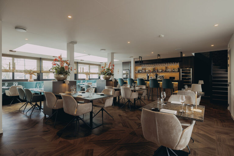 Elegant restaurant interieur met donkere tafels, beige stoelen, een bar met teal krukken en een geometrische houten vloer.