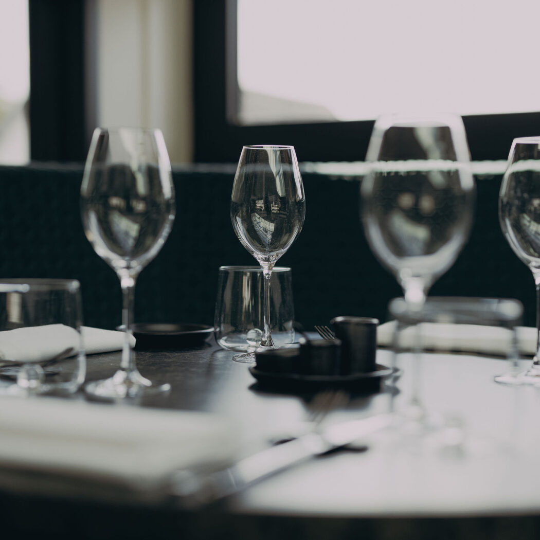 Elegante gedekte restauranttafel met wijnglazen, waterglazen, witte servetten en bestek.