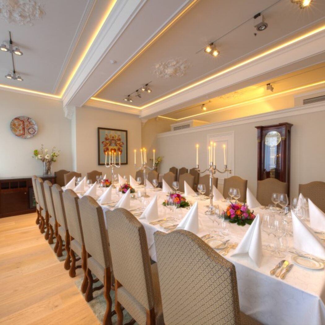 Feestelijk gedekte lange eettafel met zilveren kandelabers en bloemstukken in een stijlvolle zaal.