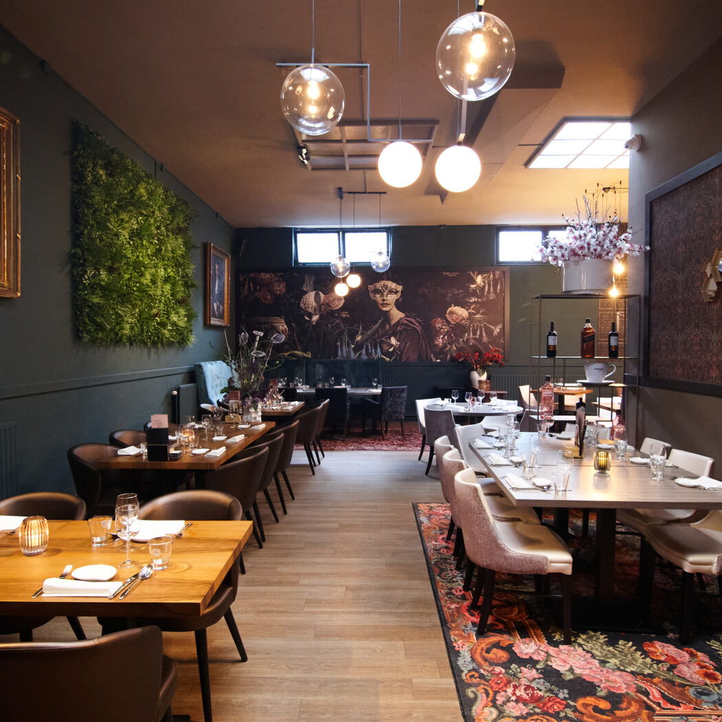 Sfeervol restaurantinterieur met donkere muren, houten tafels en kunstzinnige decoraties.