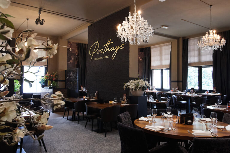 Restaurant Posthuys Hotel met luxe gedekte tafels, kristallen kroonluchters en gouden naamschild op donkere muur.