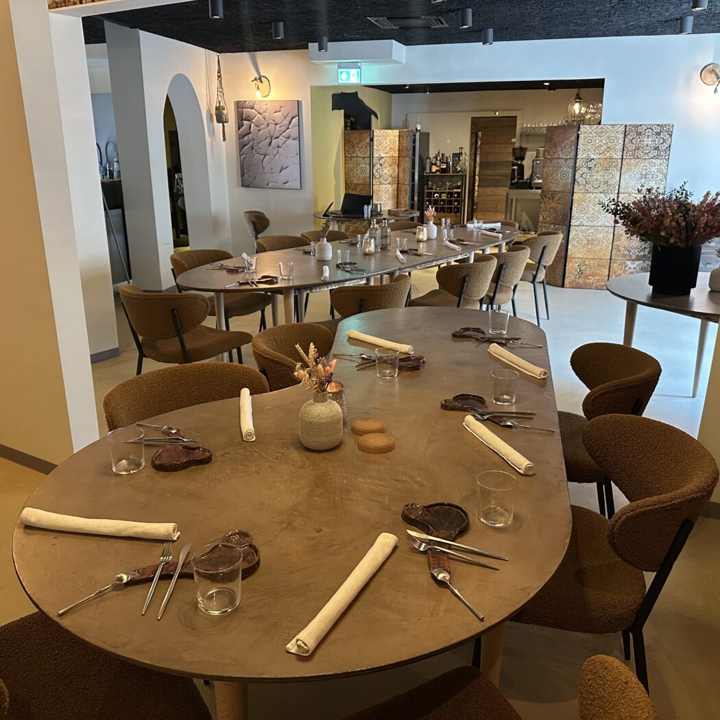 Een sfeervol restaurantinterieur met ovale tafels, donkerbruine stoelen en gedekte plaatsen.