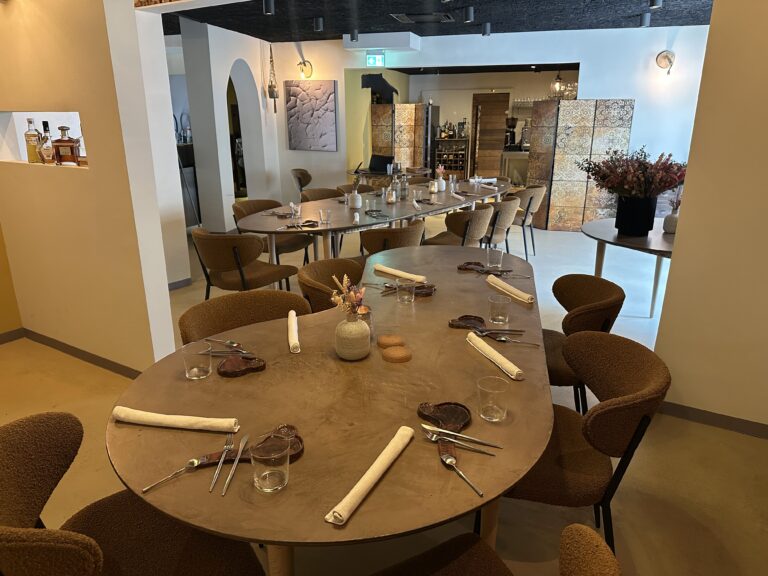 Een sfeervol restaurantinterieur met ovale tafels, donkerbruine stoelen en gedekte plaatsen.