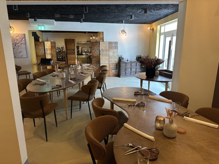 Gezellig restaurantinterieur met gedekte tafels, bruine stoelen en sfeervolle verlichting.