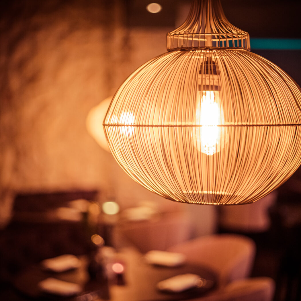 Gouden ronde draadkooi hanglamp met Edison gloeilamp in sfeervol interieur.