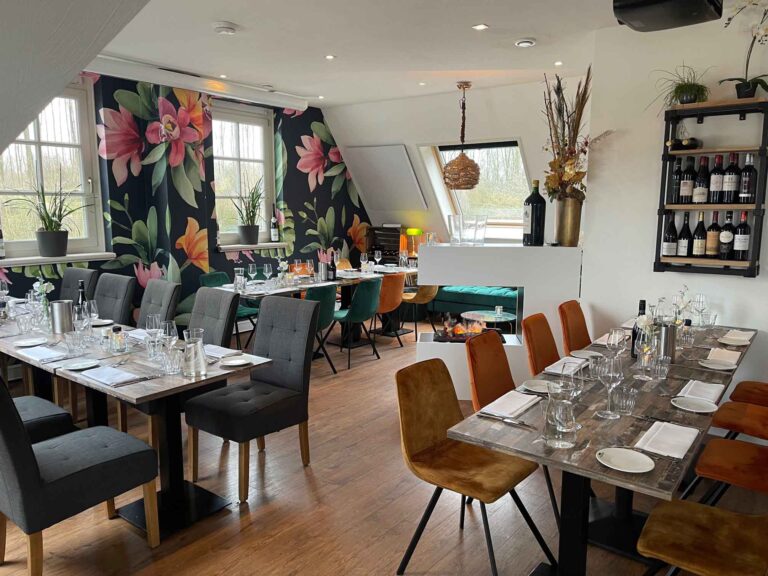 Sfeervolle restaurant dinerruimte met gedekte tafels, bloemenbehang, een moderne open haard en een wijnrek.