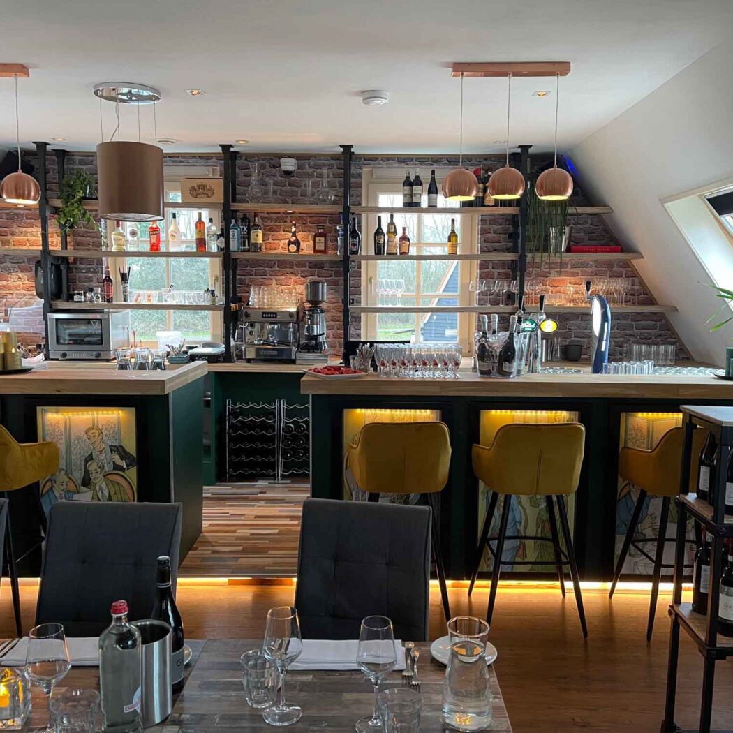 Sfeervol restaurantinterieur met houten bar, gele barstoelen, bakstenen muur en gevulde wijn- en drankrekken.