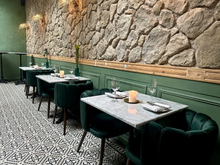 Restaurantinterieur: marmeren tafels, fluwelen stoelen, stenen muur.