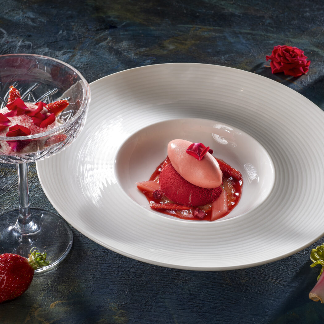 Twee luxe aardbei-rozen desserts: roze sorbet op een wit bord en romig fruit in een coupeglas, met verse rabarber.