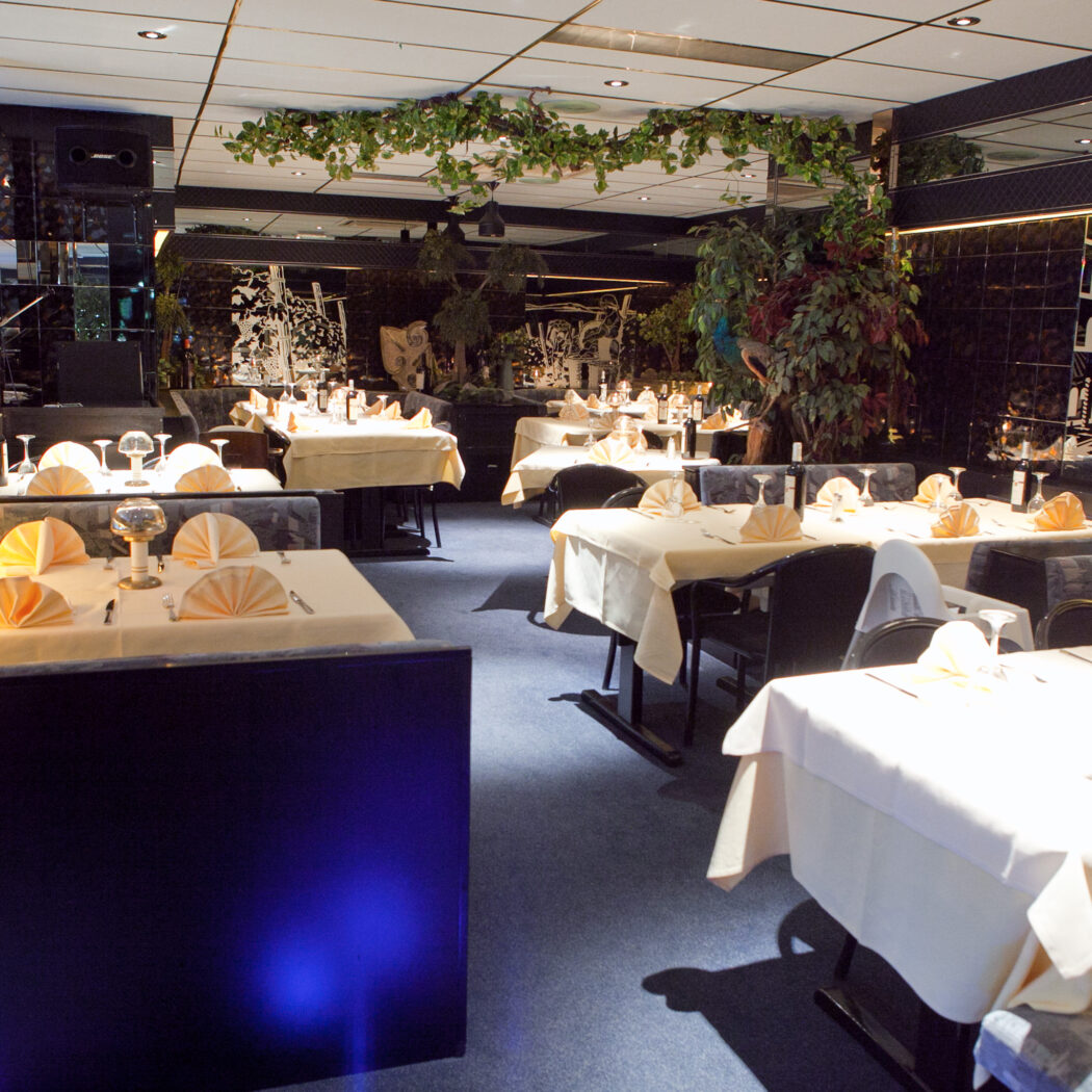 Lege restaurant eetzaal met gedekte tafels, spiegelwanden, Venetiaanse kunst en een pianist.