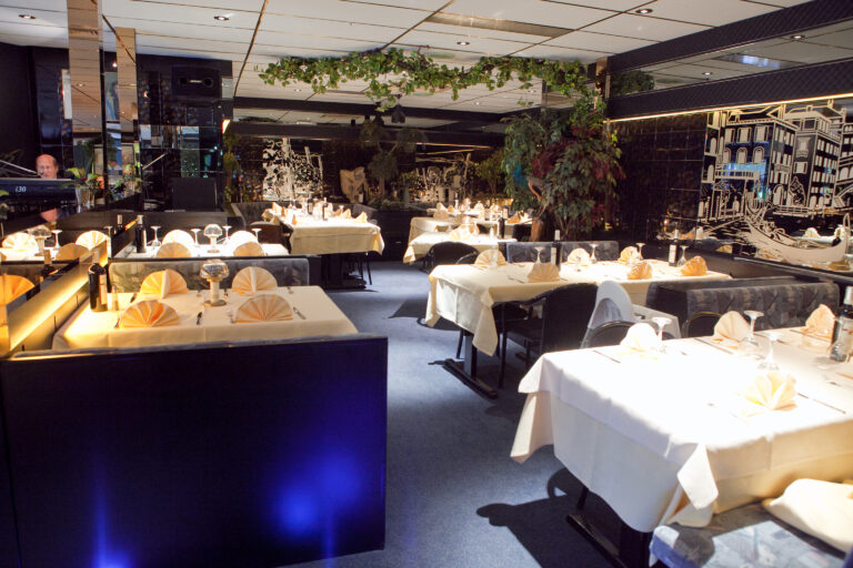 Lege restaurant eetzaal met gedekte tafels, spiegelwanden, Venetiaanse kunst en een pianist.