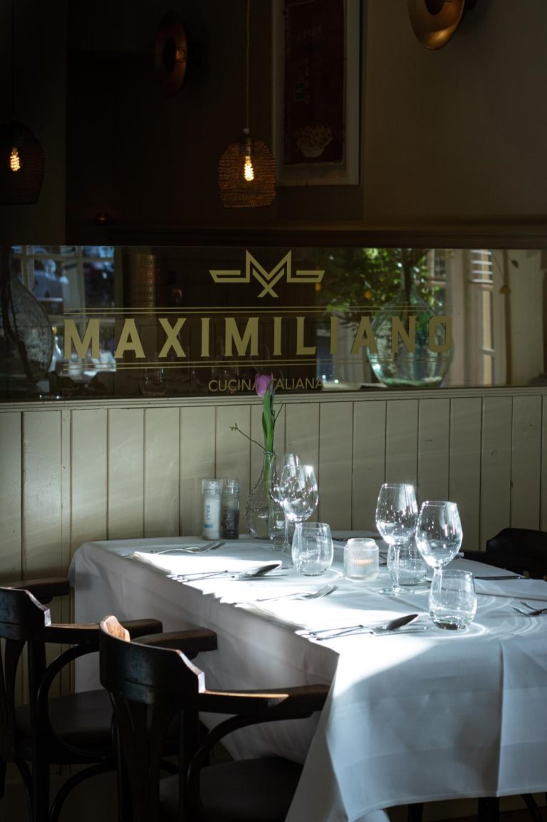 Gedekte tafel in restaurant Maximiliano Cucina Italiana met wijnglazen, bestek en tulp.