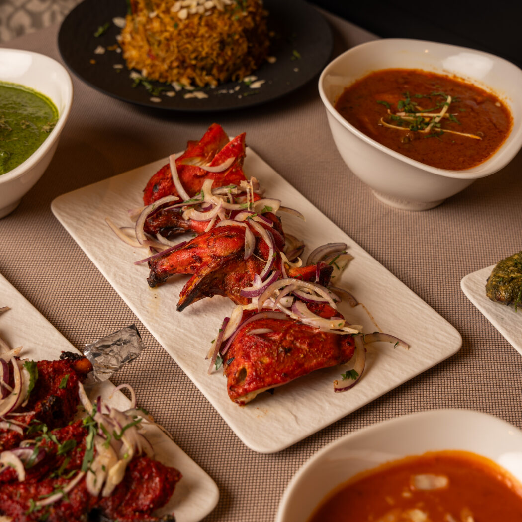Een uitgebreide selectie Indiase gerechten: tandoori kip, rode kebabs, groene curry en romige rode sauzen.