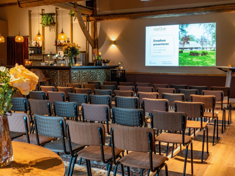 Sfeervolle vergaderzaal met rijen bruine en grijze stoelen, projectiescherm Draadloos presenteren en bar.