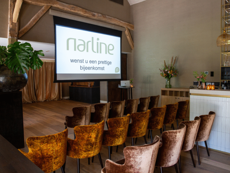 Een moderne vergaderruimte met narline presentatie op scherm, bruine en oranje velvet stoelen en een bar.