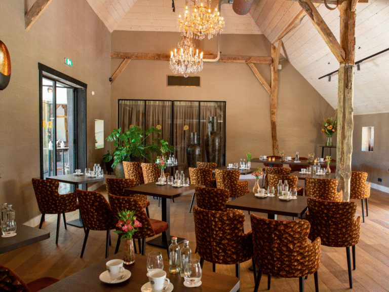 Ruime eetzaal met bruine stoelen, gedekte tafels, houten balken en kristallen kroonluchters.