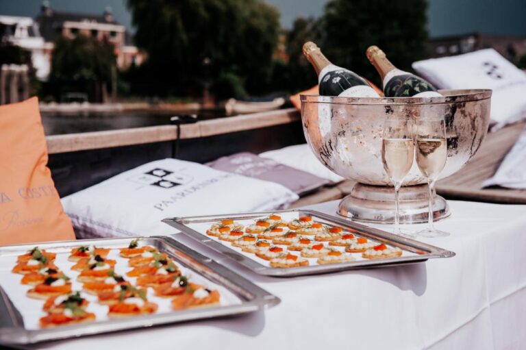 Zalm- en viseitjes-canapés op trays, met twee glazen en champagne in een zilveren koeler op een boot.