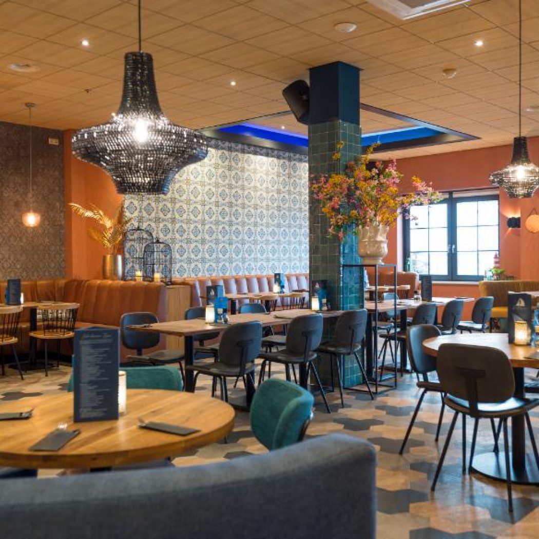 Modern restaurant met houten tafels, bruine zitbanken, tegelpatroonbehang, koi vis art en zwarte kroonluchters.