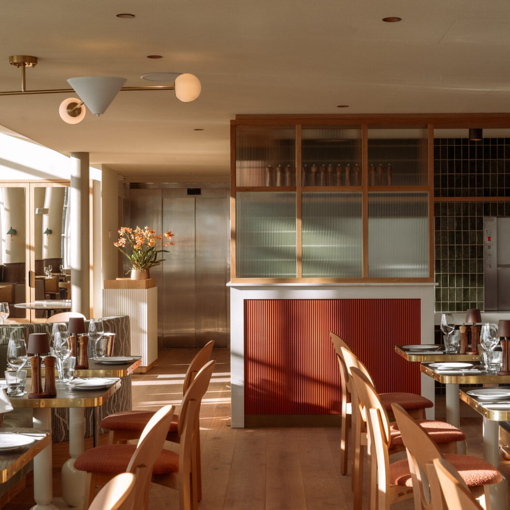 Stijlvol restaurant interieur met opgedekte tafels, houten stoelen en terracotta accenten in warm zonlicht.