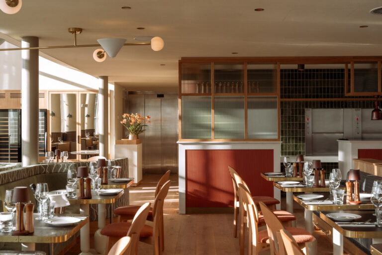 Stijlvol restaurant interieur met opgedekte tafels, houten stoelen en terracotta accenten in warm zonlicht.