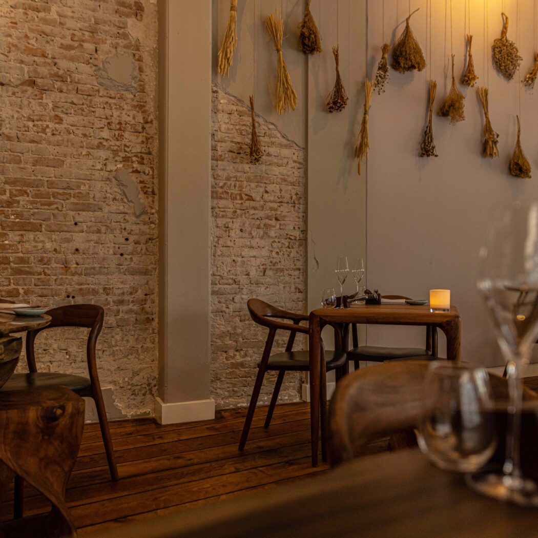 Sfeervol restaurantinterieur met gedekte houten tafels, een bakstenen muur en gedroogde kruiden decoratie.
