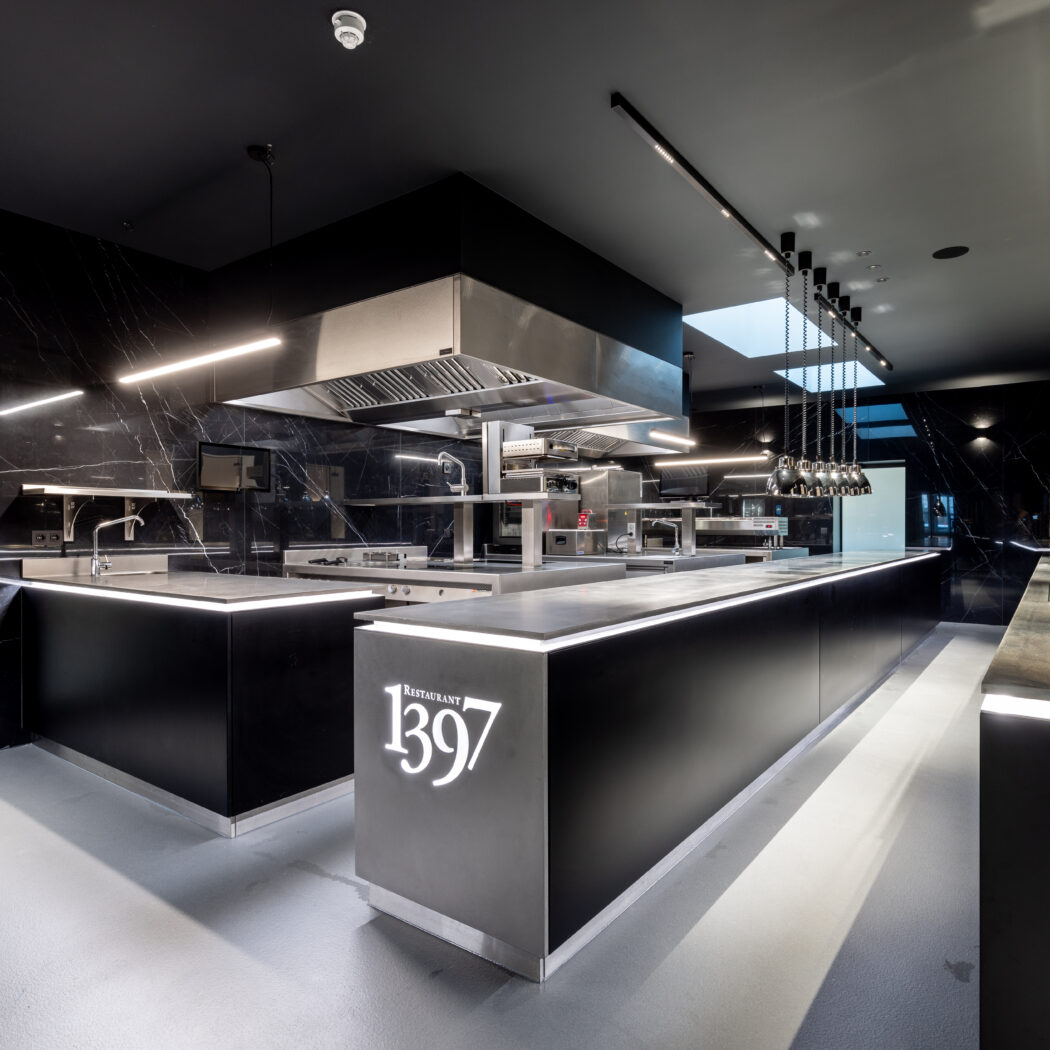 Strakke, moderne professionele keuken met zwarte marmeren wanden, verlichte balies en logo RESTAURANT 1397.